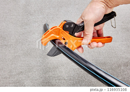 Ratchet pipe cutter is cutting flexible HDPE tube. 116935108