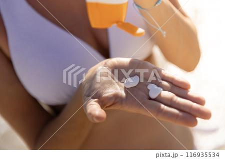 Young woman in bikini spreading sunscreen on a beach in summer 116935534