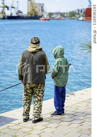 Retired elderly man goes fishing with his grandson from pier. Family active lifestyle 116936193
