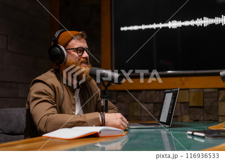 A modern podcast host wearing headphones in a professional recording studio setting A modern podcast host wearing headphones in a professional recording studio setting 116936533