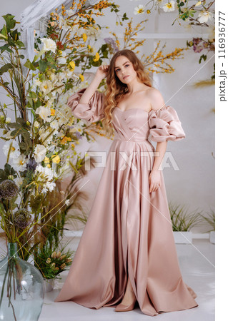 A beautiful woman in a full-length lush pink dress. A beautiful woman in a full-length lush pink dress. 116936777