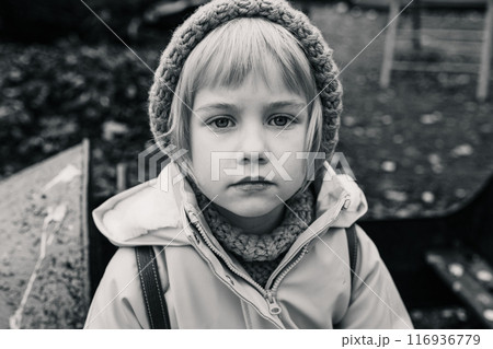 A young girl wearing a hat and a jacket is looking at the camera 116936779