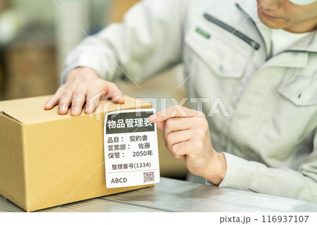 出荷ラベルを貼り付ける男性作業員　顔無し 116937107