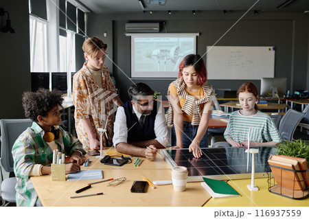 Group of ethnically diverse teen boys and girls learning about solar energy and PV modules during Environmental Education lesson 116937559