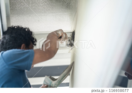 Close up to Plastering from Asian man's hand who plaster the top of the wall to protect insect and rat enter into the inside. Close up to Plastering from Asian man's hand who plaster the top of the wall to protect insect and rat enter into the inside. 116938077