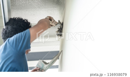 Close up to Plastering from Asian man's hand who plaster the top of the wall to protect insect and rat enter into the inside. 116938079