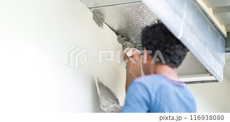 Close up to Plastering from Asian man's hand who plaster the top of the wall to protect insect and rat enter into the inside. 116938080
