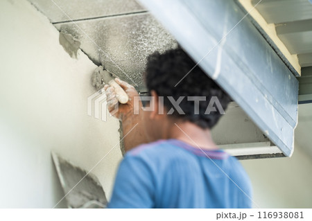 Close up to Plastering from Asian man's hand who plaster the top of the wall to protect insect and rat enter into the inside. Close up to Plastering from Asian man's hand who plaster the top of the wall to protect insect and rat enter into the inside. 116938081