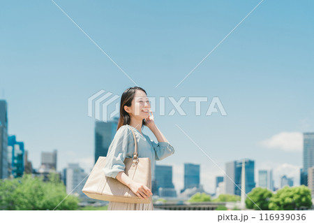 青空とビル群を背景にしたビジネスウーマン 116939036