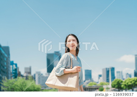 青空とビル群を背景にしたビジネスウーマン 116939037