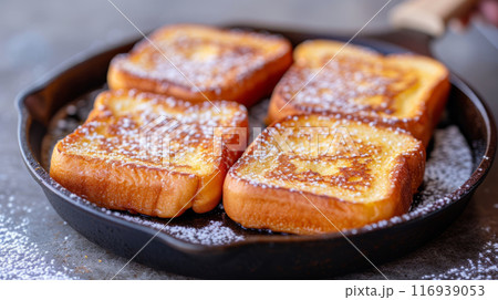 Delicious French toasts in a skillet sprinkled with powdered sugar, ideal for breakfast or brunch 116939053