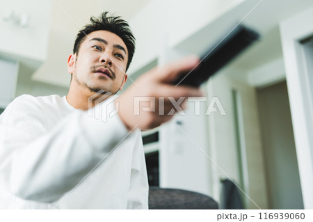 テレビを見る男性とリモコン 116939060