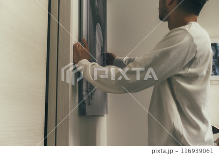 絵を飾る男性の手 116939061
