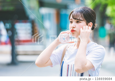 猛暑に耐えペットボトルで体を冷やす若い女性 116939084