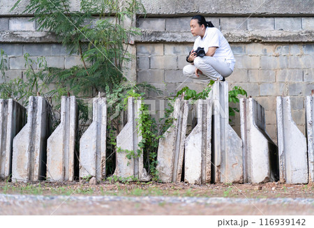 Asian Professional cameraman sits and thinks about how to create a creativity photo in the construction area background and environment. 116939142