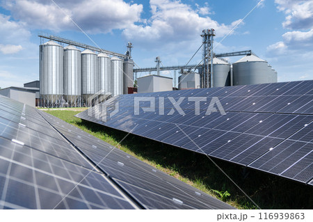 Modern farm using renewable energy. Solar panels with silos in the background. Modern farm using renewable energy. Solar panels with silos in the background. 116939863