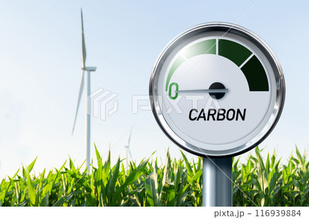 Gauge with inscription CARBON. Arrow points to zero. Agricultural field and wind turbines in the background. Concept of carbon neutral bio fuel Gauge with inscription CARBON. Arrow points to zero. Agricultural field and wind turbines in the background. Concept of carbon neutral bio fuel 116939884