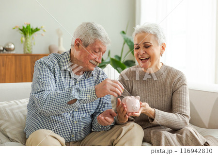 Saving money investment for future. Senior adult mature couple holding piggy bank putting money coin. Old man woman counting saving money planning retirement budget. Saving investment banking concept Saving money investment for future. Senior adult mature couple holding piggy bank putting money coin. Old man woman counting saving money planning retirement budget. Saving investment banking concept 116942810