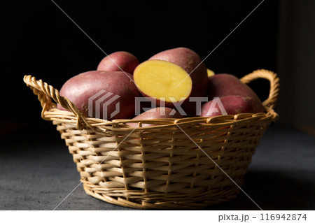 Beautiful pink new potatoes in a wicker basket, low angle 116942874