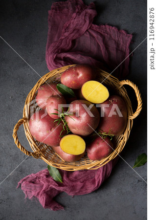 Beautiful pink new potatoes in a wicker basket on the fabric 116942876