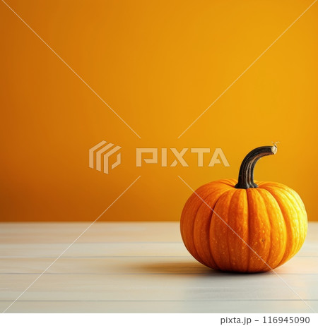 Single Pumpkin on White Table Against Orange Background 116945090