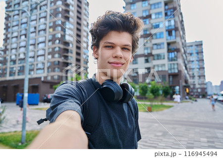 Selfie portrait of young handsome man with curly hair, outdoor 116945494