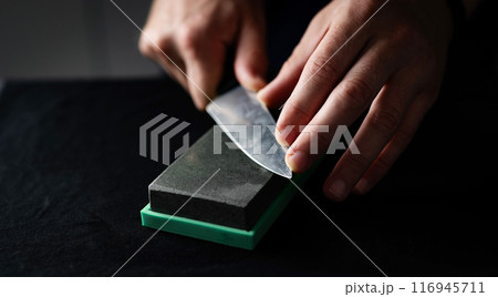 Male Hands Sharpening Kitchen Knife With Whetstone 116945711