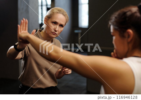 Mature boxing trainer looking at learner Mature boxing trainer looking at learner 116946128