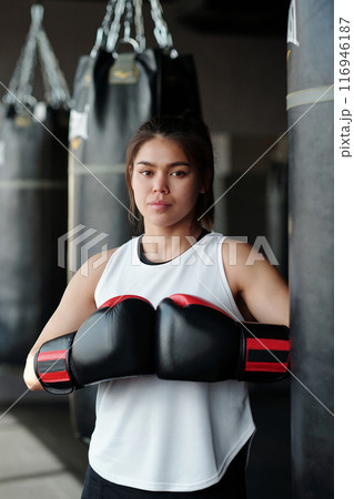 Confident young woman in boxing gloves Confident young woman in boxing gloves 116946187