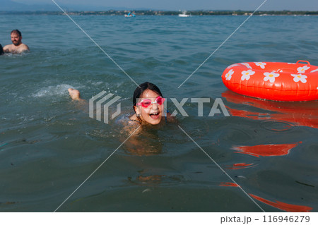 upper view of excited girl in pink goggles swimming on a sunny day in the lake upper view of excited girl in pink goggles swimming on a sunny day in the lake 116946279