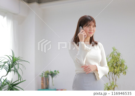 うれしそうに電話の話を聞く若い女性1 うれしそうに電話の話を聞く若い女性1 116946535