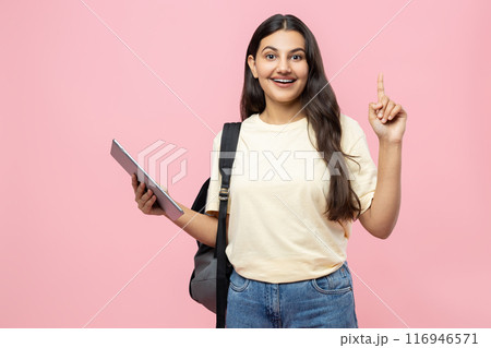 Happy young student girl with backpack and digital tablet having idea indicating upwards 116946571
