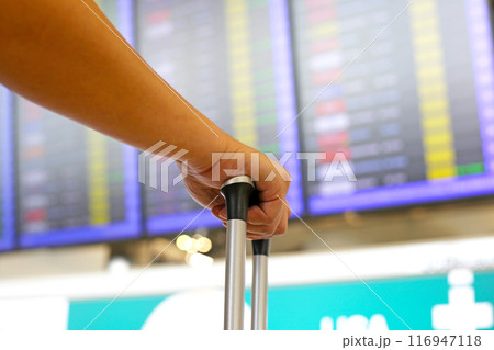 Man hand touching baggage with flight information board in international airport. Man hand touching baggage with flight information board in international airport. 116947118