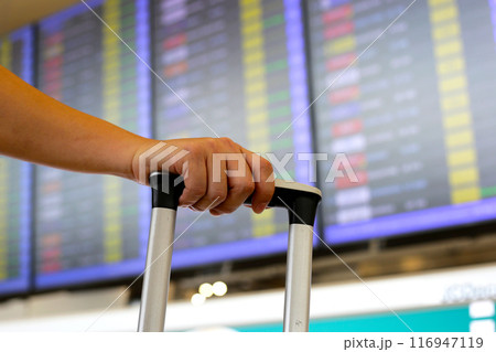 Man hand touching baggage with flight information board in international airport. Man hand touching baggage with flight information board in international airport. 116947119