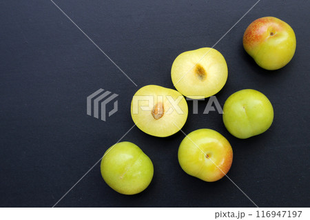 Fresh green plum fruit on dark background. Fresh green plum fruit on dark background. 116947197