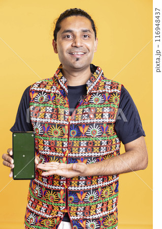 Content creator in traditional clothing recommending isolated screen phone, studio backdrop. Indian man reviewing copy space mockup smartphone device for online tech channel 116948437