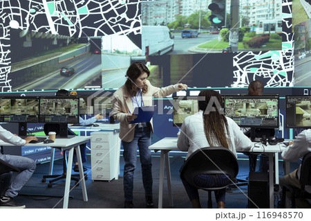 Diverse employees studying order tracking and shipment logistics to help couriers with fast delivery through city traffic. Agency utilizing CCTV system, footage and gps coordinates, pin on map. Diverse employees studying order tracking and shipment logistics to help couriers with fast delivery through city traffic. Agency utilizing CCTV system, footage and gps coordinates, pin on map. 116948570