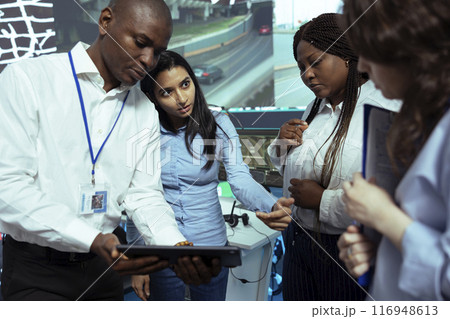 Team of diverse employees analyzing order logistics on awb papers, finding the shipment location and fixing the gps coordinates on satellite map. Group of operators work on express delivery. Team of diverse employees analyzing order logistics on awb papers, finding the shipment location and fixing the gps coordinates on satellite map. Group of operators work on express delivery. 116948613