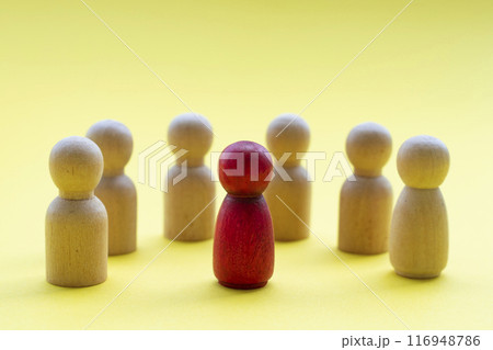 A red wooden figure surround by other wooden figures representing either someone is a leader or someone being discriminated 116948786