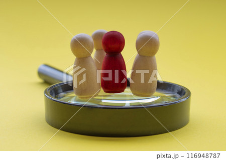 A red wooden figure with his or her team member standing on top of a magnifying glass. Leadership and business concept 116948787