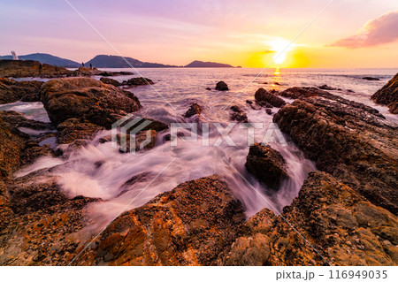 Long exposure image of Dramatic sky seascape with rocks and waves crashing on seashore in sunset or sunrise scenery background Long exposure image of Dramatic sky seascape with rocks and waves crashing on seashore in sunset or sunrise scenery background 116949035