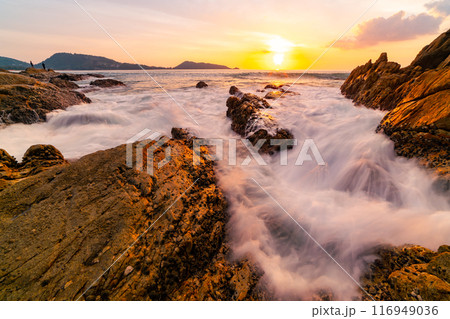 Long exposure image of Dramatic sky seascape with rocks and waves crashing on seashore in sunset or sunrise scenery background Long exposure image of Dramatic sky seascape with rocks and waves crashing on seashore in sunset or sunrise scenery background 116949036