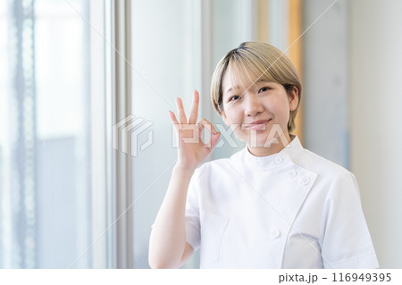 ケーシー白衣を着る金髪ショートヘアの若い女性整体師（髪色自由、自分らしく働く、職場環境） 116949395