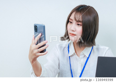 スマホを見て首を傾げる若い女性スタッフ 116949399