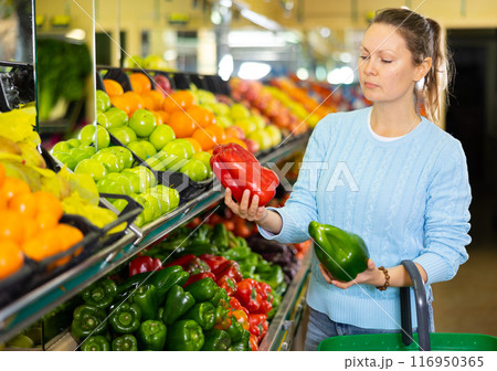 Middle-aged casual female choosing bell peppers in supermarket Middle-aged casual female choosing bell peppers in supermarket 116950365