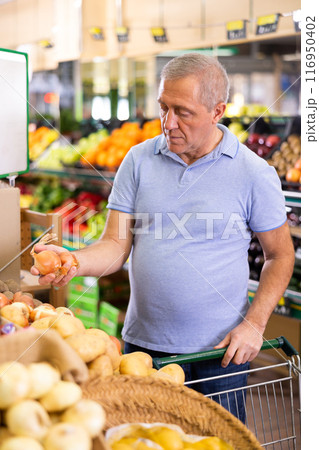 Elderly man purchaser buying onions in grocery store 116950402