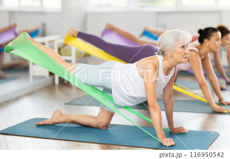Elderly woman exercises with pilates band 116950542