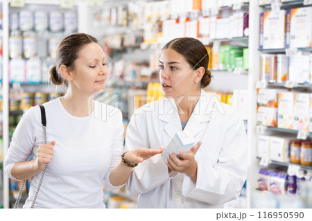 Female pharmacist advises a girl who came to the pharmacy to buy therapeutic cosmetics Female pharmacist advises a girl who came to the pharmacy to buy therapeutic cosmetics 116950590