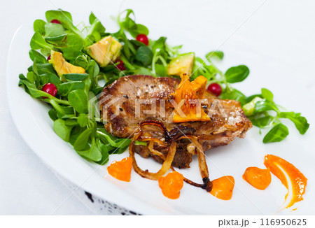 Cooked fried pork meat with herbs, sauce and berries on plate 116950625