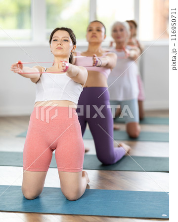 Young woman exercising with pilates band 116950711